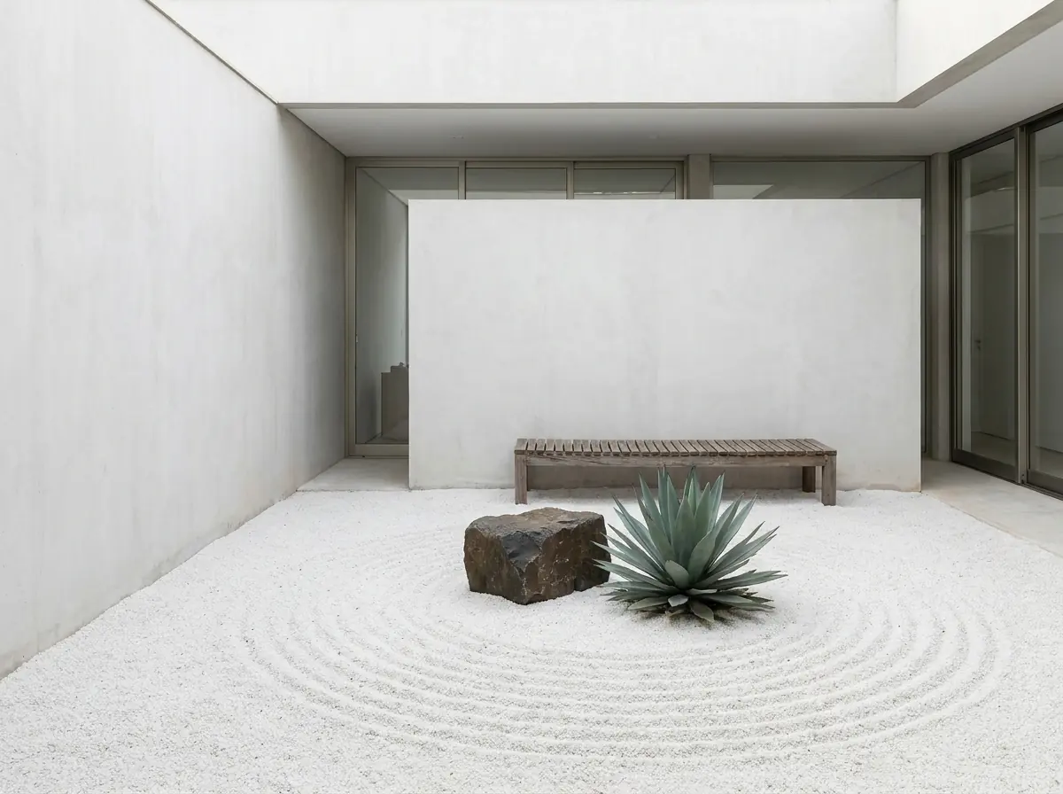 Pátio minimalista coberto com malha branca rastelada em linhas, com uma rocha escura e uma agave